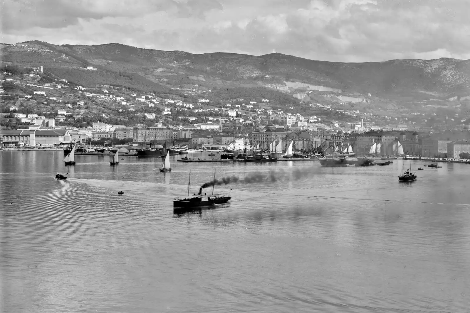 The port of Trieste seen from the sea in the early twentieth century, with sailing ships and steamers before the quays.